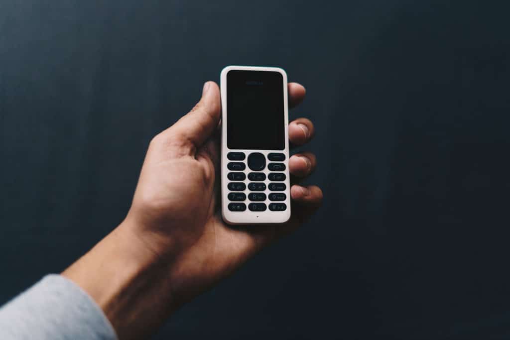 A hand holds an older-style cell phone