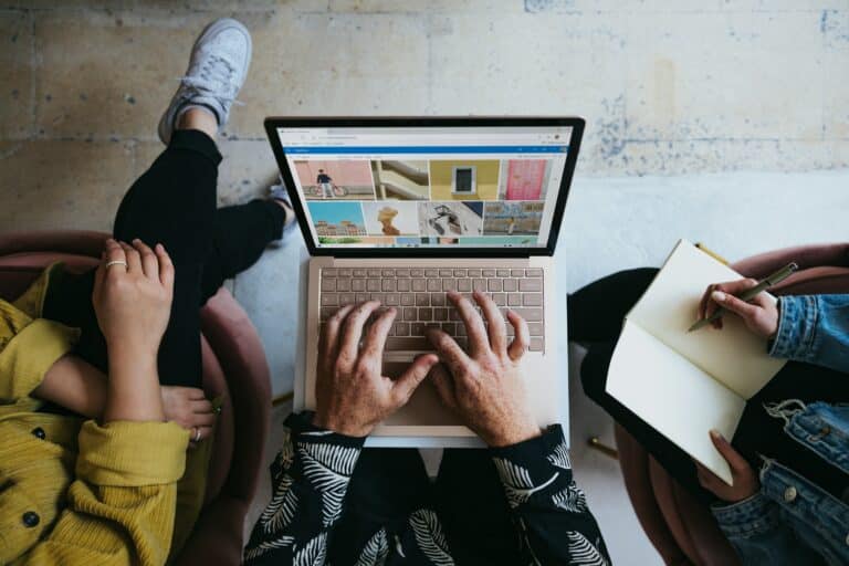 three people working around a laptop by Windows